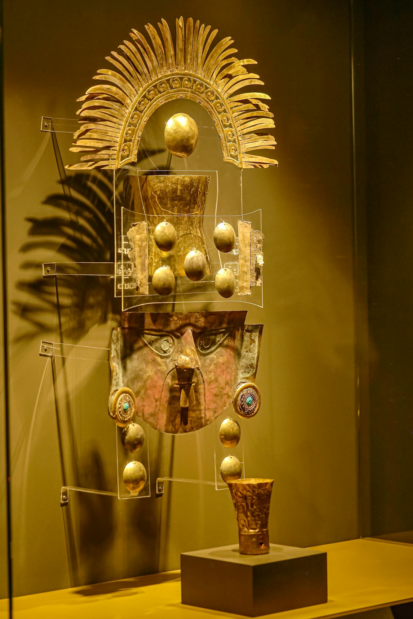 A stunning ancient Inca gold headdress exhibited in a museum showcase.