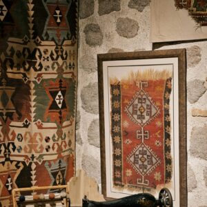 Vintage Anatolian textiles and antique sewing machine in a stone-walled room in Ankara, Türkiye.